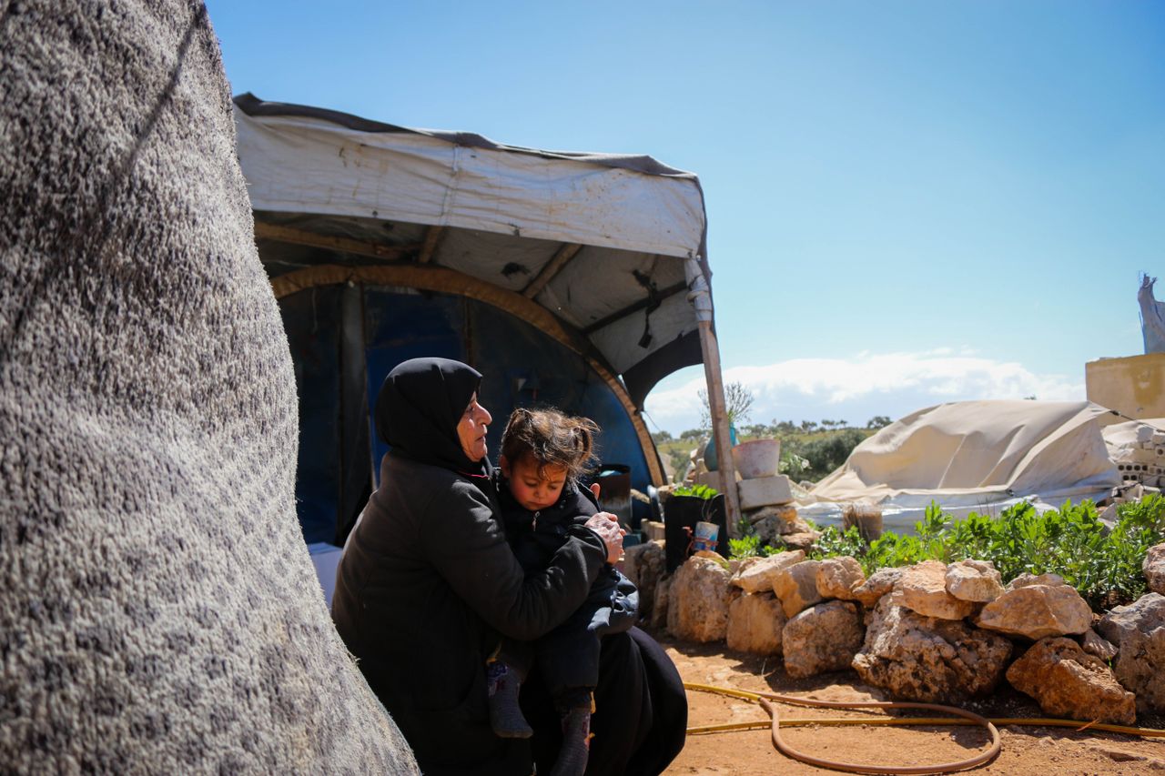 A mother comforts her child in a Syrian refugee camp, highlighting resilience and family bonds.
